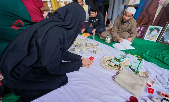 A Shiite Muslim woman donates her ring during a relief drive for Iran in Budgam, Indian-controlled Kashmir, Monday, March 23, 2026. (AP Photo/Mukhtar Khan)