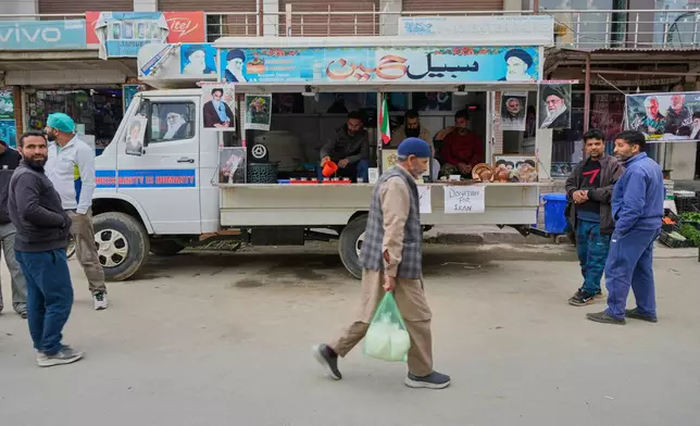 People walk past a van collecting donations for Iran in Budgam, Indian-controlled Kashmir, Monday, March 23, 2026. (AP Photo/Mukhtar Khan)