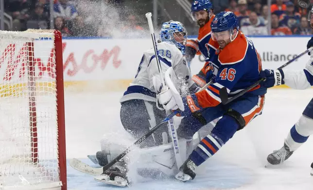 Tampa Bay Lightning goalie Andrei Vasilevskiy (88) is crashed into by Edmonton Oilers' Max Jones (46) during second period NHL action, in Edmonton on Saturday March 21, 2026. (Jason Franson/The Canadian Press via AP)