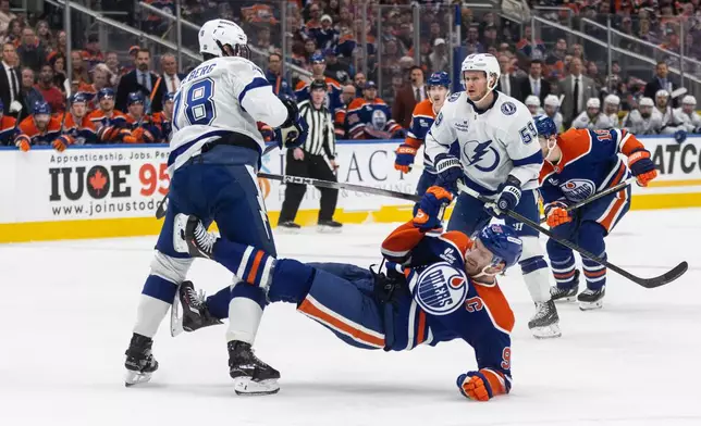 Tampa Bay Lightning's Emil Lilleberg (78) checks Edmonton Oilers' Connor McDavid (97) during second period NHL action, in Edmonton on Saturday March 21, 2026. (Jason Franson/The Canadian Press via AP)