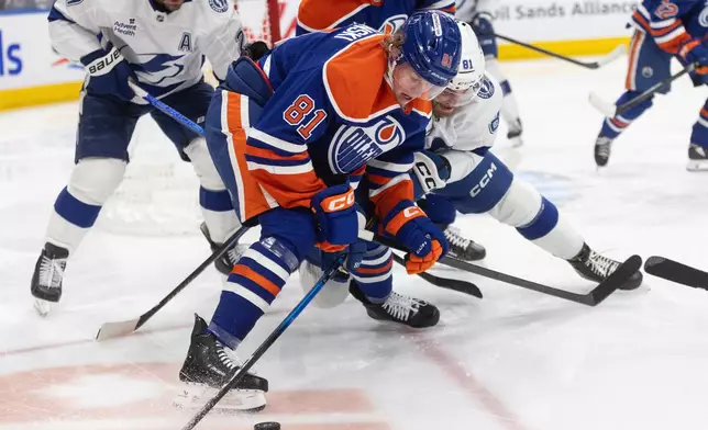 Tampa Bay Lightning's Erik Cernak (front) and Edmonton Oilers' Josh Samanski battle for the puck during second period NHL action, in Edmonton on Saturday March 21, 2026. (Jason Franson/The Canadian Press via AP)