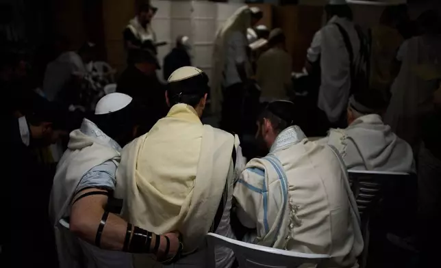 Jewish men covered in prayer shawls pray in an underground parking garage as a precaution against possible Iranian missile attacks, in Tel Aviv, Israel, Tuesday, March 3, 2026. (AP Photo/Oded Balilty)