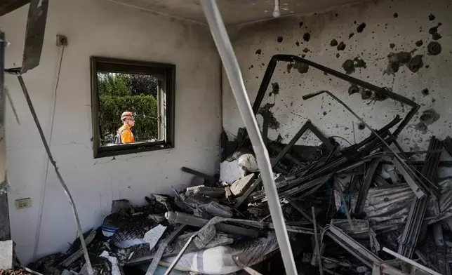 Israeli authorities inspect homes damaged by a projectile launched from Lebanon, in Haniel, central Israel, Thursday, March 12, 2026. (AP Photo/Baz Ratner)