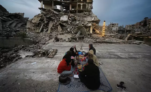 Members of the Al-Najar family break their fast during the Muslim holy month of Ramadan amid the rubble of destroyed buildings in Gaza City Friday, March 13, 2026. (AP Photo/Jehad Alshrafi)