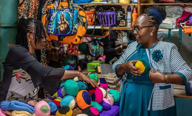 Nancy Waithera, right, tries on a knitted breast prosthesis as Mary Mwangi, 52, looks on at her shop in Thika, Kiambu County, Kenya, Friday, Jan. 30, 2026. (AP Photo/Samson Otieno)