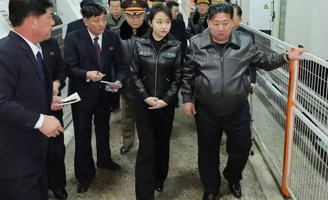 In this photo provided by the North Korean government, its leader Kim Jong Un, right, and his daughter visit a factory producing pistols and other light arms at an undisclosed place in North Korea Wednesday, March 11, 2026. Independent journalists were not given access to cover the event depicted in this image distributed by the North Korean government. The content of this image is as provided and cannot be independently verified. (Korean Central News Agency/Korea News Service via AP)