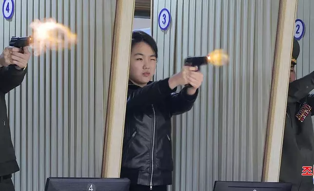 In this photo provided by the North Korean government, its leader Kim Jong Un's daughter, center, tries out a new pistol at a factory producing pistols and other light arms at an undisclosed place in North Korea Wednesday, March 11, 2026. Independent journalists were not given access to cover the event depicted in this image distributed by the North Korean government. The content of this image is as provided and cannot be independently verified. Korean language watermark on image as provided by source reads: "KCNA" which is the abbreviation for Korean Central News Agency. (Korean Central News Agency/Korea News Service via AP)