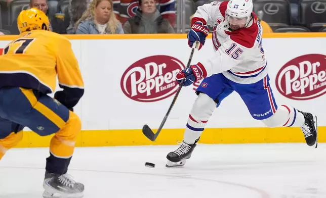 Montreal Canadiens center Alex Newhook (15) shoots the puck past Nashville Predators center Tyson Jost (17) during the first period of an NHL hockey game Saturday, March 28, 2026, in Nashville, Tenn. (AP Photo/George Walker IV)
