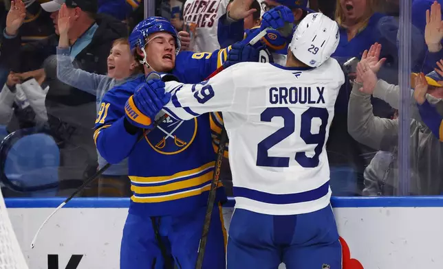 Buffalo Sabres right wing Josh Doan (91) and Toronto Maple Leafs center Bo Groulx (29) tie each other up behind the net during the first period of an NHL hockey game Saturday, March 14, 2026, in Buffalo, N.Y. (AP Photo/Jeffrey T. Barnes)