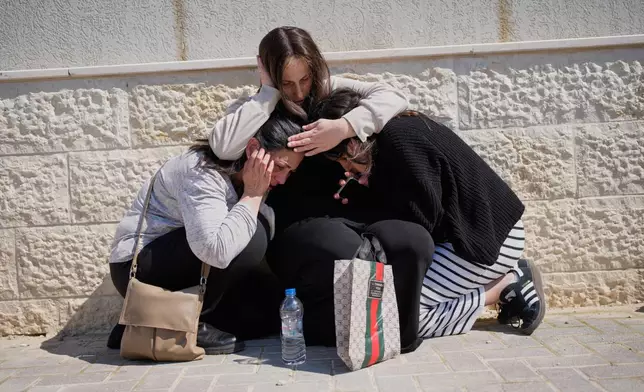 Mourners take cover while air-raid sirens warn of incoming missiles launched by Iran toward Israel during the funeral of Sarah Elimelech and her daughter Ronit who were killed in an Iranian missile attack, in Beit Shemesh, Israel, Monday, March 2, 2026. (AP Photo/Ohad Zwigenberg)