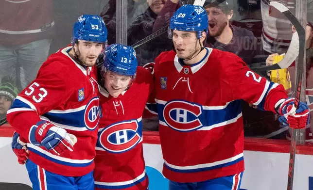 Montreal Canadiens' Cole Caufield (13) celebrates his goal on the Carolina Hurricanes with teammates Noah Dobson (53) and Juraj Slafkovsky (20) during the second period of an NHL hockey game in Montreal on Tuesday, March 24, 2026. (Christinne Muschi/The Canadian Press via AP)