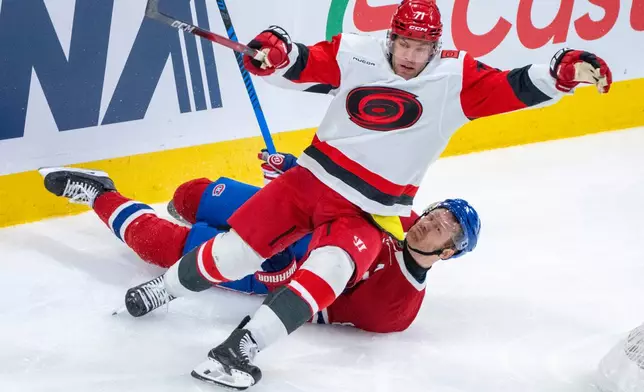 Montreal Canadiens' Mike Matheson (8) gets tangled up with Carolina Hurricanes' Taylor Hall (71) during the second period of an NHL hockey game in Montreal on Tuesday, March 24, 2026. (Christinne Muschi/The Canadian Press via AP)