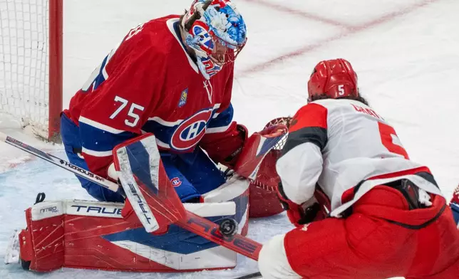 Montreal Canadiens goaltender Jakub Dobes (75) stops a shot by Carolina Hurricanes' Jalen Chatfield (5) during the second period of an NHL hockey game in Montreal, Tuesday, March 24, 2026. (Christinne Muschi/The Canadian Press via AP)