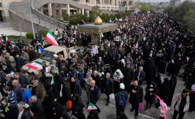 People follow a truck carrying the flag draped coffins of Gen. Ali Mohammad Naeini, a spokesperson for Iran’s paramilitary Revolutionary Guard and one of his comrades Amir Hossein Bidi , during their funeral procession in Tehran, Iran, Saturday, March 21, 2026. (AP Photo/Vahid Salemi)
