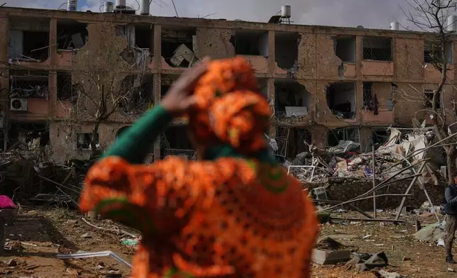 People survey a site that was struck by an Iranian missile in Dimona, southern Israel, Sunday, March 22, 2026. (AP Photo/Ariel Schalit)