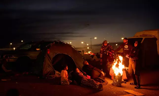 Members of a family, who fled Israeli strikes in southern Lebanon, sit around a bonfire outside a tent used as a shelter in Beirut, Lebanon, Wednesday, March 25, 2026. (AP Photo/Emilio Morenatti)