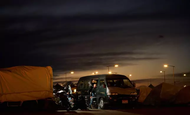 A man who fled Israeli strikes in southern Lebanon smokes in his van with his family outside a tent used as a shelter in Beirut, Lebanon, Wednesday, March 25, 2026. (AP Photo/Emilio Morenatti)