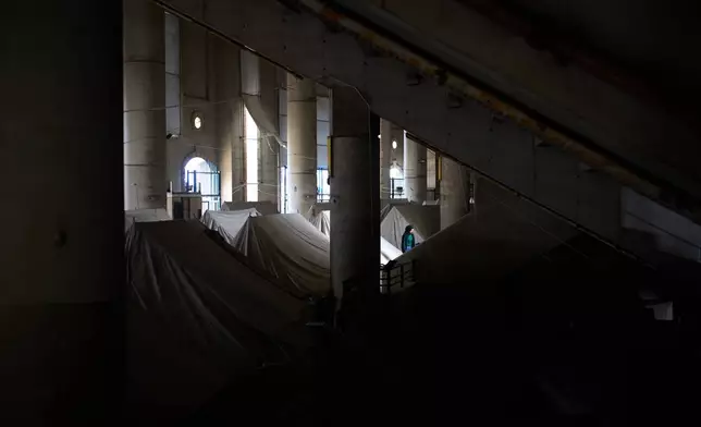 A displaced woman walks next to tents set up inside the Camille Chamoun Sports City Stadium, which has been turned into a shelter for people displaced by Israeli airstrikes in southern Lebanon, in Beirut, Lebanon, Monday, March 30, 2026. (AP Photo/Emilio Morenatti)