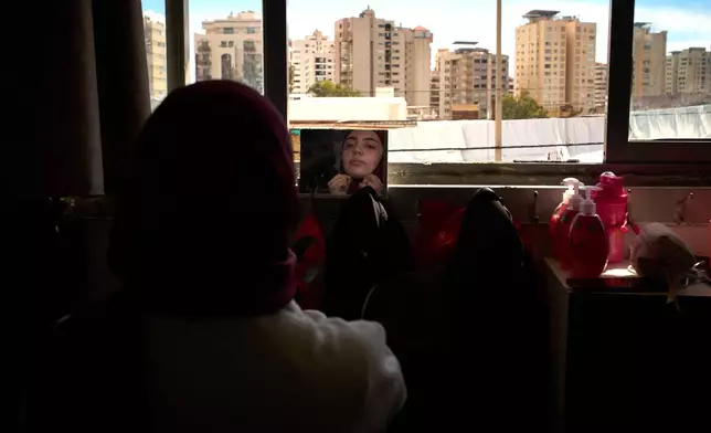Nour Zahraa Almokdad, 19, displaced from Beirut's southern suburb of Haret Hreik, adjusts her veil in front of a mirror in a school used as a shelter in Beirut, Lebanon, Wednesday, March 25, 2026. (AP Photo/Emilio Morenatti)