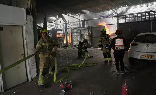 Firefighters try to extinguish a fire at a damaged workshop struck by an Iranian missile in Petah Tikva, Israel, Tuesday, March 31, 2026. (AP Photo/Oded Balilty)
