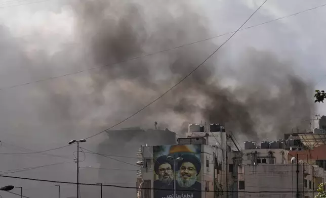 Portraits of Hezbollah's late leaders Hassan Nasrallah, right, and his cousin, Hashem Safieddine, are seen, as smoke rises following an Israeli airstrike in Dahiyeh, Beirut's southern suburbs, Lebanon, Monday, March 30, 2026. (AP Photo/Hassan Ammar)
