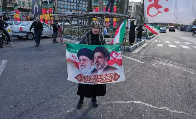 A woman holds a banner showing portraits of the late Iranian Supreme Leader Ayatollah Ali Khamenei, left, and his son Ayatollah Mojtaba Khamenei, the successor to him, during a campaign in support of the government at the Enqelab-e-Eslami, or Islamic Revolution, square in downtown Tehran, Iran, Monday, March 30, 2026. (AP Photo/Vahid Salemi)