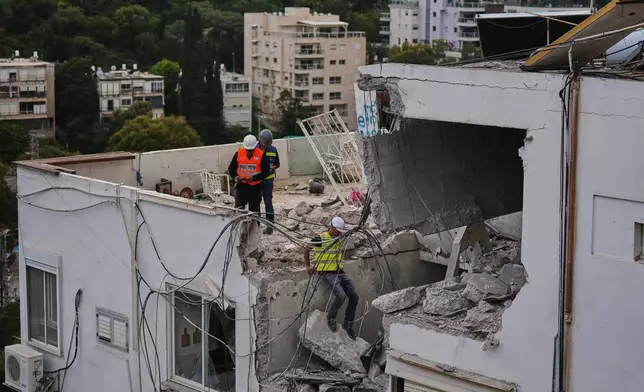 Israeli authorities inspect a damaged house following an Iranian missile strike in Haifa, Israel, Monday, March 30, 2026. (AP Photo/Ariel Schalit)