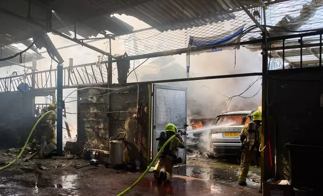 Firefighters try to extinguish a fire at a damaged workshop struck by an Iranian missile in Petah Tikva, Israel, Tuesday, March 31, 2026. (AP Photo/Oded Balilty)