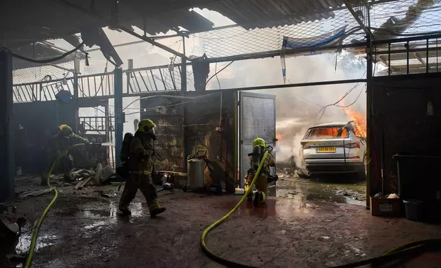 Firefighters try to extinguish a fire at a damaged workshop struck by an Iranian missile in Petah Tikva, Israel, Tuesday, March 31, 2026. (AP Photo/Oded Balilty)
