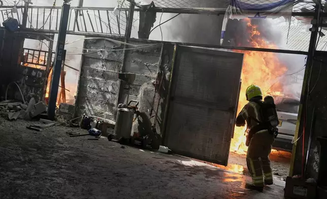 A firefighter battles flames at a damaged workshop after an alert of incoming missiles in Petah Tikva, Israel, Tuesday, March 31, 2026. (AP Photo/Oded Balilty)