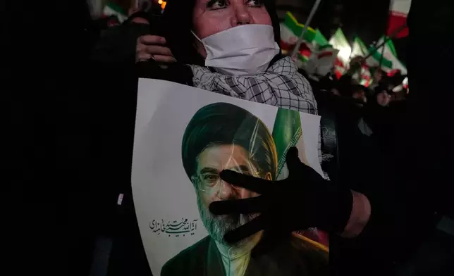 A woman holds a picture of the Iranian Supreme Leader Ayatollah Mojtaba Khamenei during a pro-government gathering in a square in western Tehran, Iran, Wednesday, March 25, 2026. (AP Photo/Vahid Salemi)