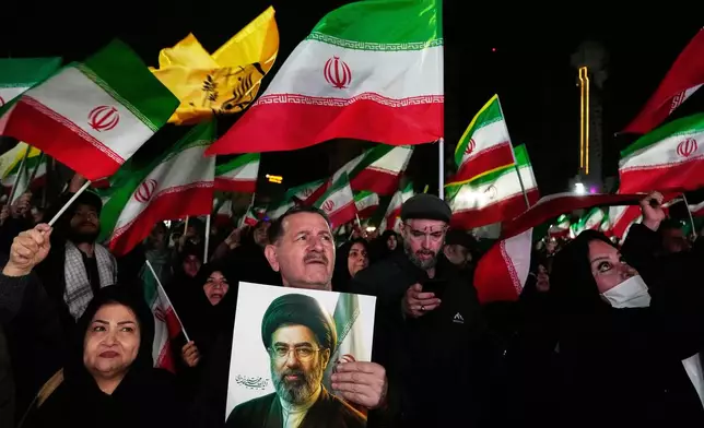 Pro-government supporters wave national flags as one of them holds a picture of the Supreme Leader Ayatollah Mojtaba Khamenei during a rally in a square in western Tehran, Iran, Wednesday, March 25, 2026. (AP Photo/Vahid Salemi)