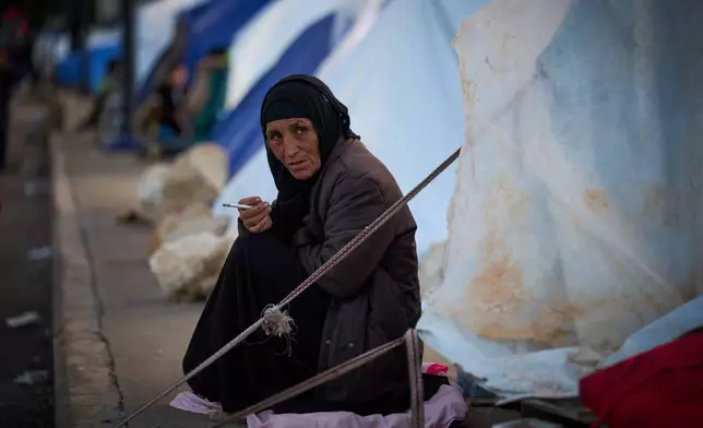 A woman who fled Israeli strikes in southern Lebanon sits outside a tent used as a shelter in Beirut, Lebanon, Wednesday, March 25, 2026. (AP Photo/Emilio Morenatti)