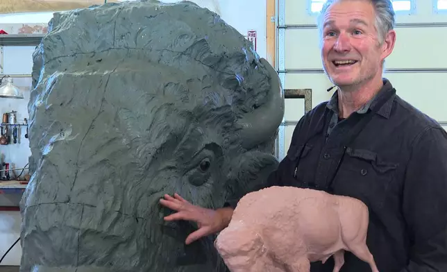 Paleoartist Gary Staab holds a small-scale prototype of a bison sculpture while standing next to the full-size clay sculpture he crafted at his studio in Kearney, Mo., on Tuesday, Dec. 2, 2025. (AP Photo/Nick Ingram)