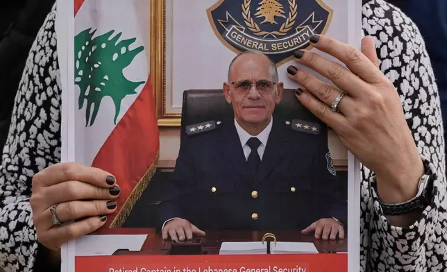 A relative of retired Lebanese officer Ahmed Shukr, holds a poster of him during a gathering outside the headquarters of the U.N. Economic and Social Commission for Western Asia, ESCWA, in Beirut, Lebanon, Friday, Feb. 13, 2026. (AP Photo/Bilal Hussein)