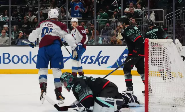 Colorado Avalanche center Nathan MacKinnon (29) reacts to scoring with center Nazem Kadri (91) against Seattle Kraken goaltender Joey Daccord (35) as center Frederick Gaudreau (89) looks on during the first period of an NHL hockey game Thursday, March 12, 2026, in Seattle. (AP Photo/Lindsey Wasson)