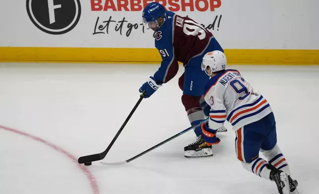Colorado Avalanche center Nazem Kadri, top, looks to pass the puck as Edmonton Oilers center Ryan Nugent-Hopkins defends in the third period of an NHL hockey game Tuesday, March 10, 2026, in Denver. (AP Photo/David Zalubowski)