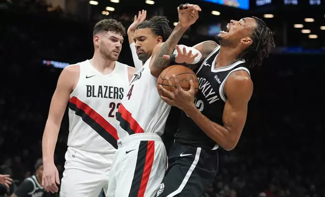 Portland Trail Blazers' Matisse Thybulle (4) and Donovan Clingan (23) defend Brooklyn Nets' Nic Claxton (33) during the first half of an NBA basketball game Monday, March 16, 2026, in New York. (AP Photo/Frank Franklin II)