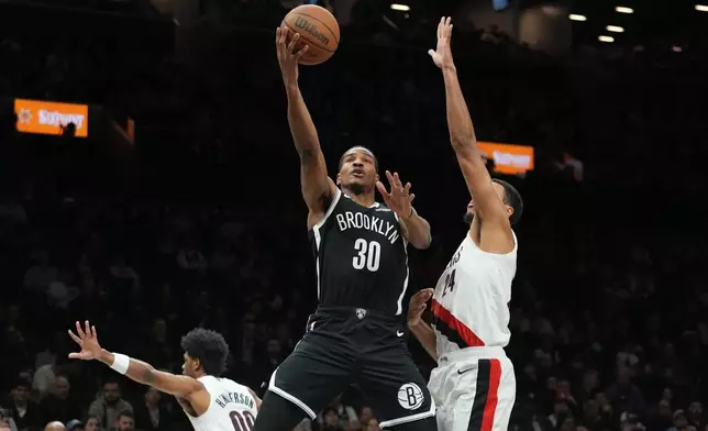 Brooklyn Nets' Ochai Agbaji (30) shoots over Portland Trail Blazers' Kris Murray (24) and Scoot Henderson (00) during the first half of an NBA basketball game Monday, March 16, 2026, in New York. (AP Photo/Frank Franklin II)