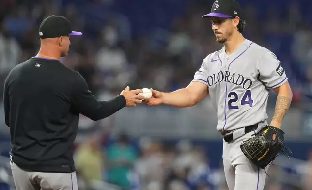 Colorado Rockies pitcher Michael Lorenzen (24) hand the bal to manager Warren Schaeffer, left, after being relieved during the fifth inning of a baseball game against the Miami Marlins, Saturday, March 28, 2026, in Miami. (AP Photo/Lynne Sladky)