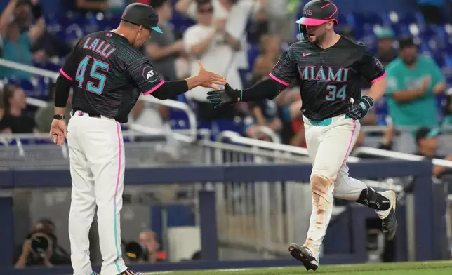Miami Marlins' Liam Hicks (34) is met by third base coach Blake Lalli (45) after hitting a two run home run during the fifth inning of a baseball game against the Colorado Rockies, Saturday, March 28, 2026, in Miami. (AP Photo/Lynne Sladky)