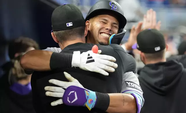 Colorado Rockies' Ezequiel Tovar is embraced in the dugout after hitting a two run home run during the fourth inning of a baseball game against the Miami Marlins, Saturday, March 28, 2026, in Miami. (AP Photo/Lynne Sladky)