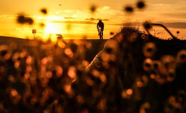 A cyclist rides on a coastal road at sunrise in Panama City, Wednesday, March 25, 2026. (AP Photo/Matias Delacroix)