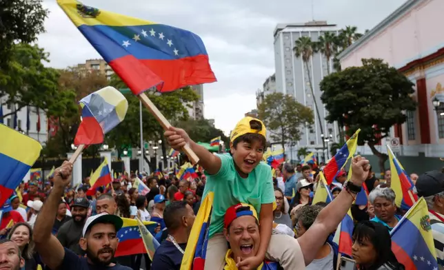Venezuela fans celebrate a day after their team's victory over the United States in the championship match of the World Baseball Classic, at the Miraflores presidential palace in Caracas, Venezuela, Wednesday, March 18, 2026. (AP Photo/Pedro Mattey)