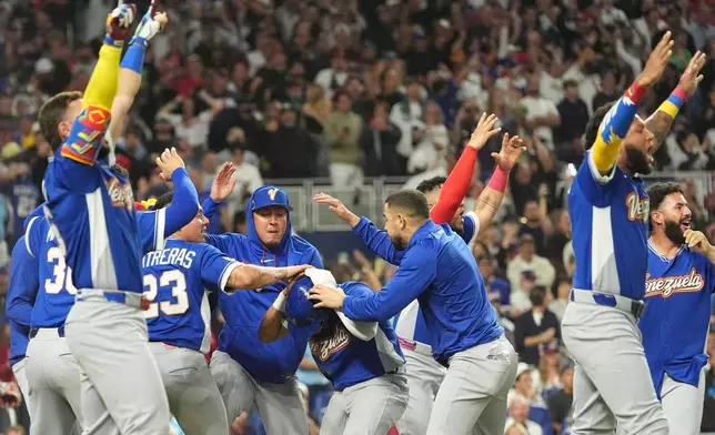 Venezuela Javier Sanoja is swarmed by his teammates after scoring during the ninth inning in the championship game of the World Baseball Classic against the United States, Tuesday, March 17, 2026, in Miami. (AP Photo/Rebecca Blackwell)