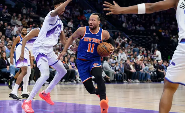 New York Knicks guard Jalen Brunson, center, drives to the basket guarded by Utah Jazz guard Ace Bailey, center left, during the first half of an NBA basketball game, Wednesday, March 11, 2026, in Salt Lake City. (AP Photo/Tyler Tate)