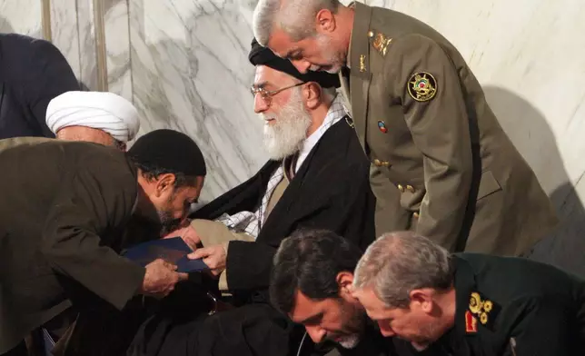FILE - An unidentified man kisses the hand of Iran's Supreme Leader Ayatollah Ali Khamenei, as Iranian Army Commander Ataollah Salehi, right standing, Major Gen. Yahya Rahim Safavi, the Commander of Islamic Revolutionary Guards Corps (IRGC), right bottom, and Culture Islamic Guidance Minister Mohammad Hossein Saffar-Harandi, second right, attend a ceremony to commemorate those who died in a plane crash in Tehran, Iran, Dec. 10, 2005. (AP Photo/Hasan Sarbakhshian, File)