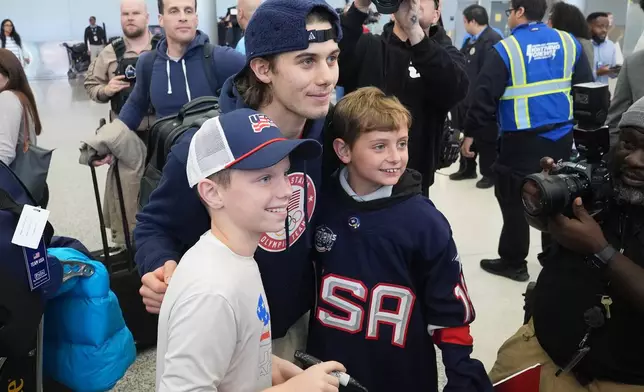 United Stated hockey player Jack Hughes poses with fans after arriving at Miami International Airport after the team won the gold medal at the Milan Cortina Olympics, Monday, Feb. 23, 2026, in Miami. (AP Photo/Marta Lavandier)