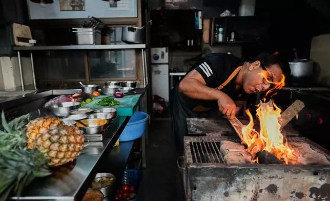 Atul Lahkar, from the Assam region, chef lights a fire with wood and coal to prepare food for his restaurant following a regional gas shortage in Guwahati, India, Thursday, March 19, 2026. (AP Photo/Anupam Nath)