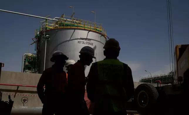 Workers stand in an area at a degassing station in Zubair oil field, whose operations have being reduced due to the Mideast war triggered by the U.S. and Israeli attacks on Iran, near Basra, Iraq, Saturday, March 28, 2026. (AP Photo/Leo Correa)